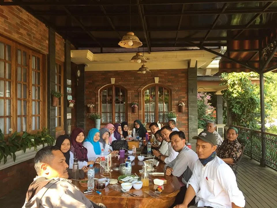 Keluarga dan teman berkumpul menikmati botram di teras kebun